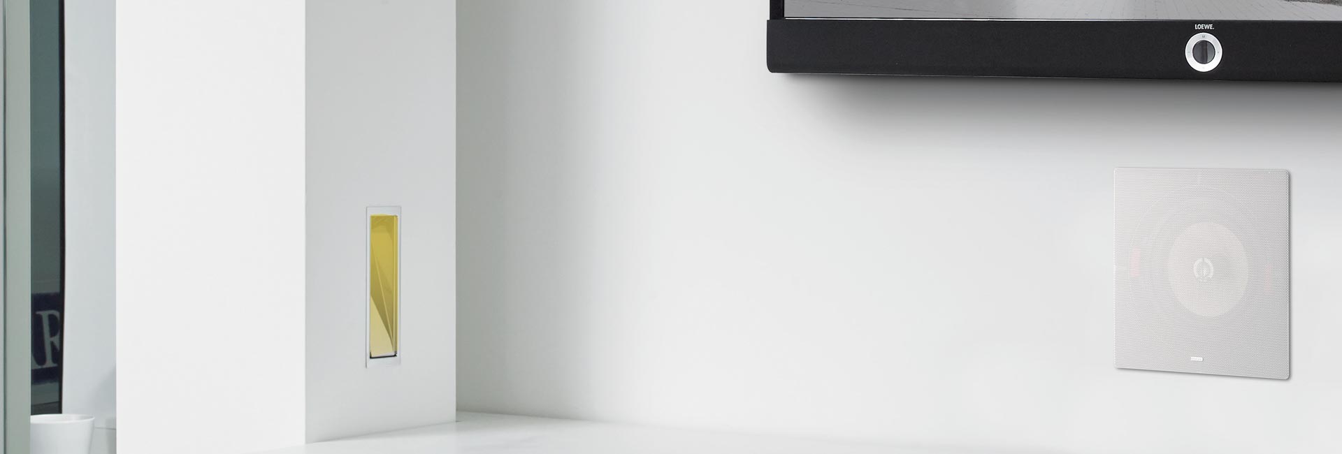 Minimal white wall with in-wall speaker and mounted TV in sleek setting